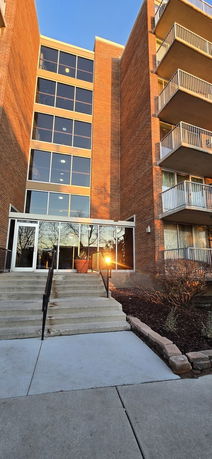 Front view of a multi-story brick building with large windows and balconies.