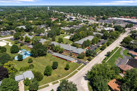 Aerial wide-angle view showing a residential area with roads, trees, and buildings.