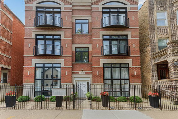 Front view of a multi-story brick building with balconies and large windows.