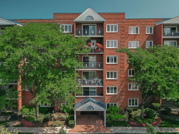 Front view of a multi-story apartment building with balconies and brick facade.