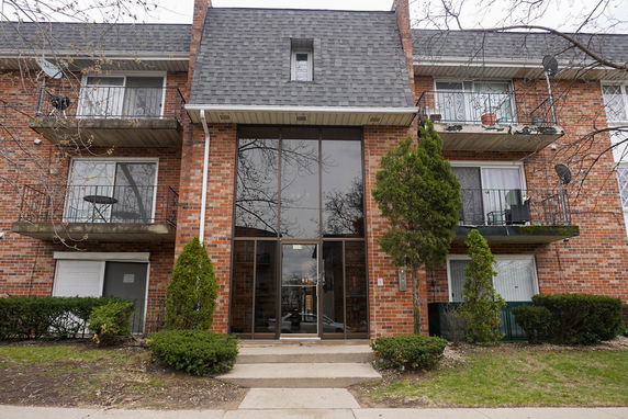Front view of a multi-story brick apartment building with balconies.