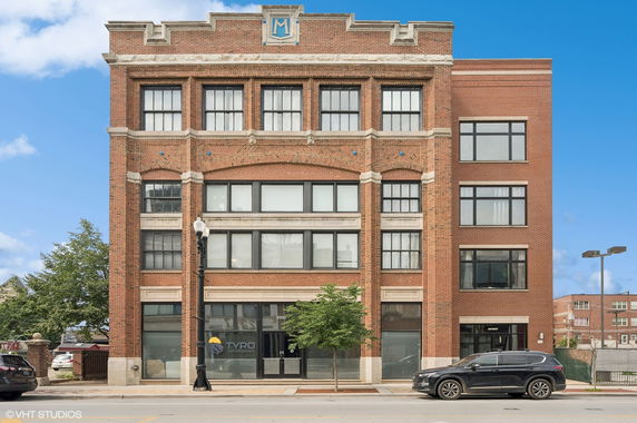 Front view of a multi-story brick building with large windows.