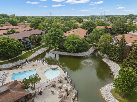 Aerial view of a residential area with a swimming pool and small pond.