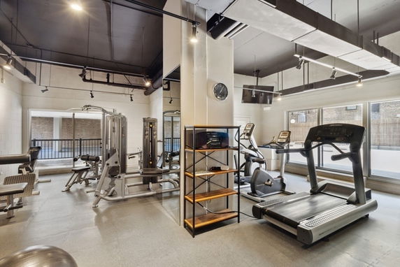 Indoor gym area with various exercise equipment and large windows.
