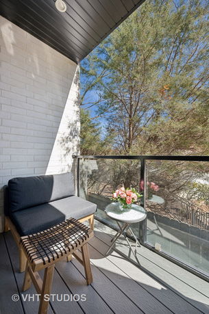 Balcony view with seating and a glass railing overlooking trees.