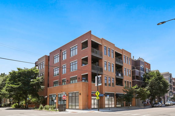 Front view of a multi-story brick building on a street corner.