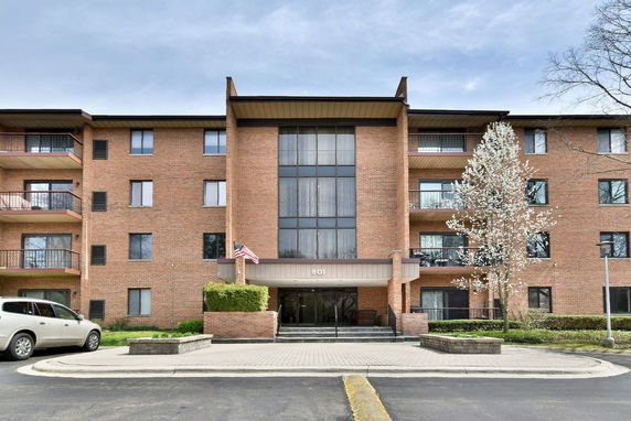 Front view of a multi-story brick apartment building with balconies and an entrance.