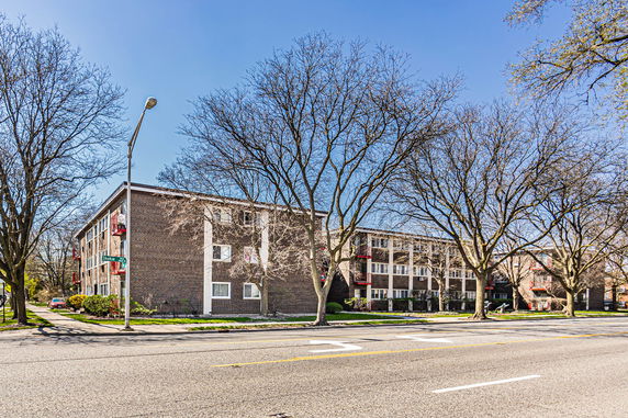 Front view of a multi-story apartment building with a brick exterior and balconies.