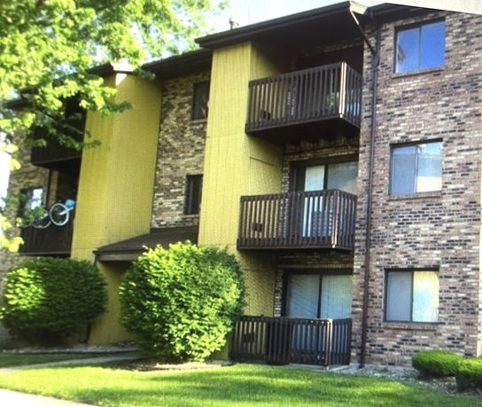 Front view of a multi-story brick apartment building with balconies.