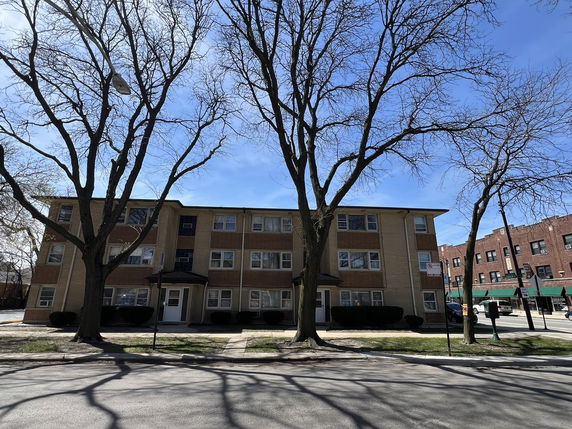 Front view of a multi-story apartment building with a brick facade.