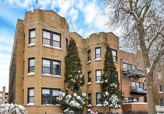 Front view of a brick apartment building with multiple windows.