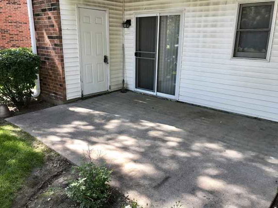 Back view of a house with a small patio area and sliding glass door.