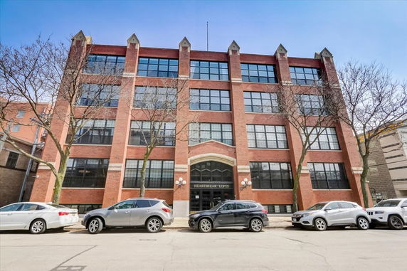 Front view of a multi-story brick building with large windows.