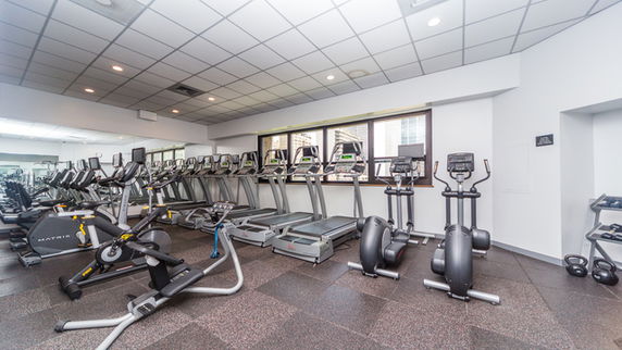 Indoor gym area with multiple exercise machines including treadmills and elliptical trainers.