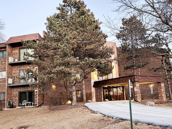 Front view of a multi-story brick building with balconies and a covered entrance.