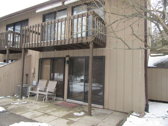 Rear view of a two-story house with a balcony and patio area.