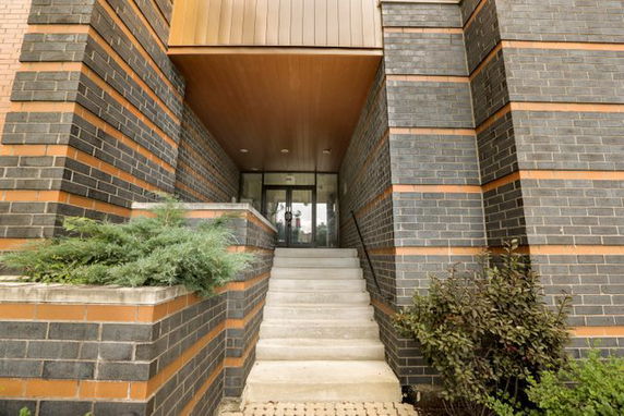 Entrance of a modern building with brick and glass facade.