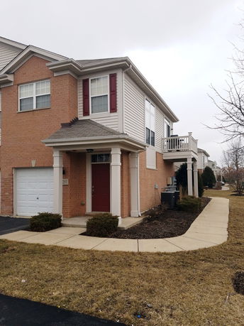 Front view of a two-story house with a red door and attached garage.