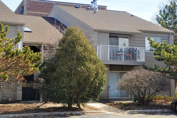 Front view of a two-story residential building with a balcony and sliding glass doors.