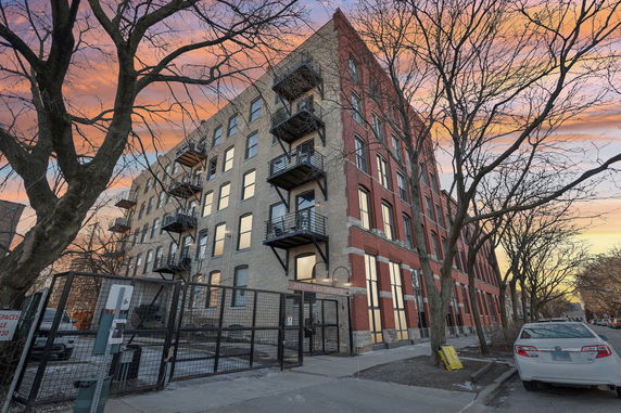 Front view of a multi-story brick apartment building with balconies.