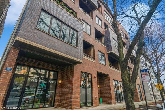 Front view of a multi-story brick building with large windows and retail space on the ground floor.