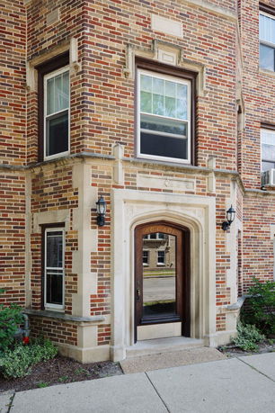 Front view of a brick apartment building entrance with decorative stonework.