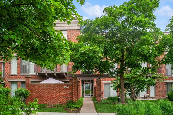 Front view of a brick residential building with balconies and large windows.