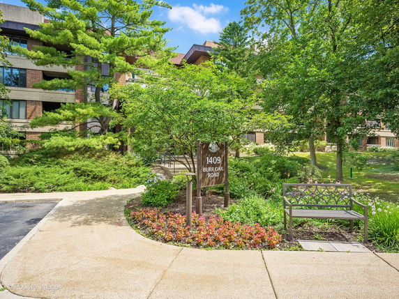 Front view of a multi-story building surrounded by trees and landscaping.