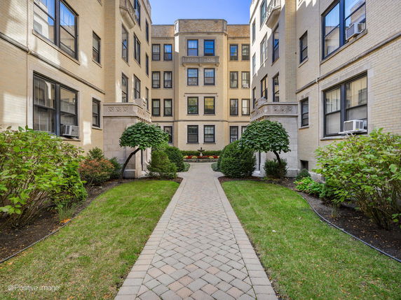 Front view of an apartment building with a pathway and landscaped garden.