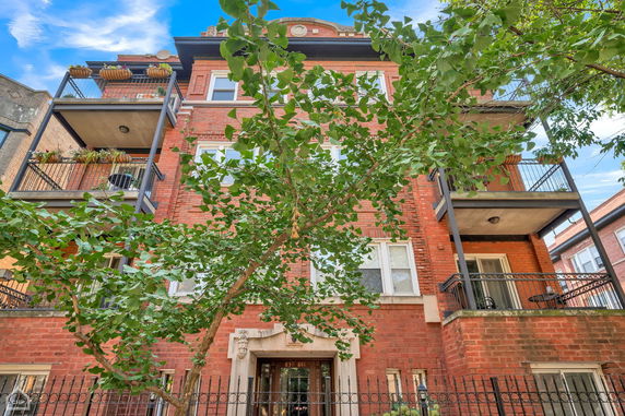 Front view of a multi-story brick apartment building with balconies.