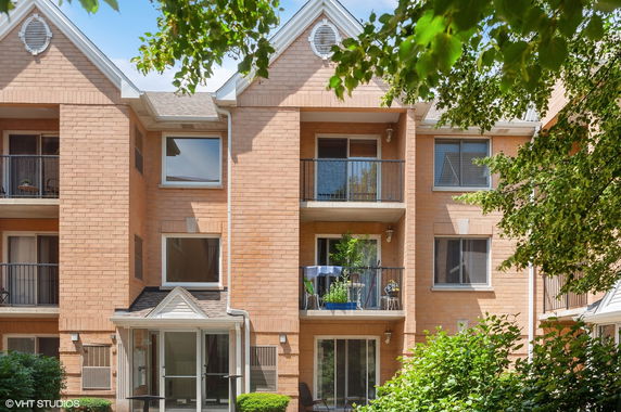 Front view of a multi-story brick apartment building with balconies.