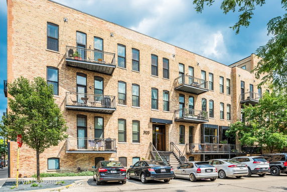 Front view of a multi-story brick apartment building with balconies.