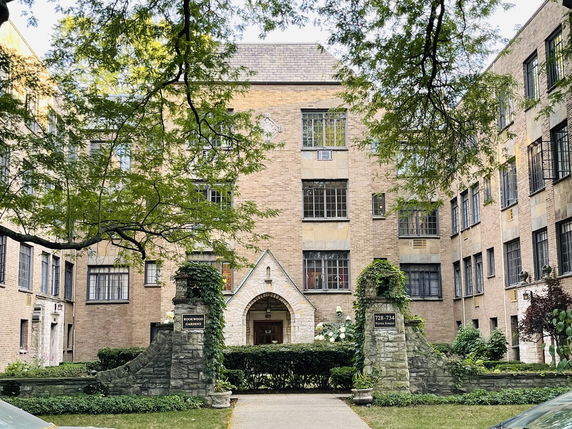 Front view of a multi-story brick residential building with archway entrance.