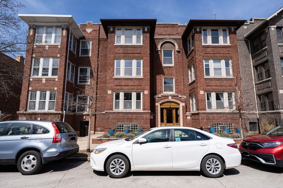 Front view of a multi-story brick building with multiple windows and an arched entrance.