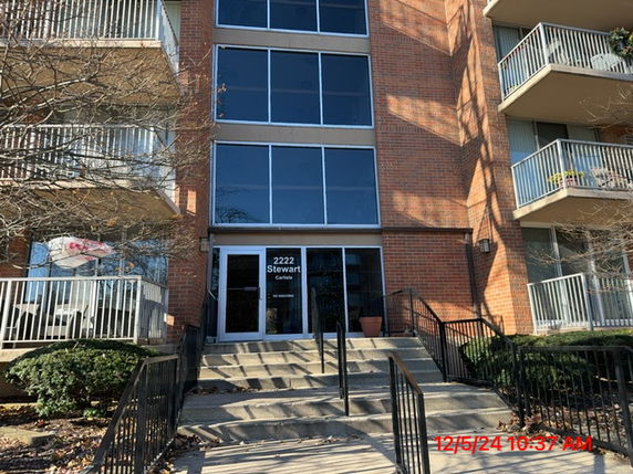 Front view of a multi-story brick building with balconies and glass entrance.