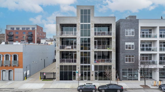 Front view of a modern multi-story building with balconies and large windows.