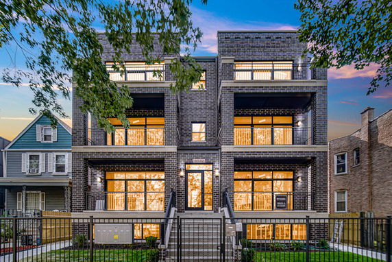 Front view of a modern multi-story brick building with balconies and large windows.