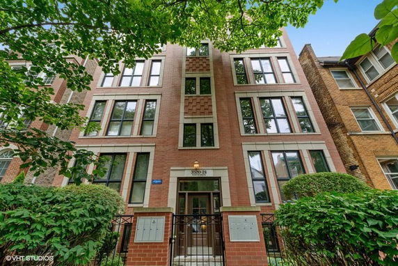 Front view of a multi-story brick apartment building with large windows.
