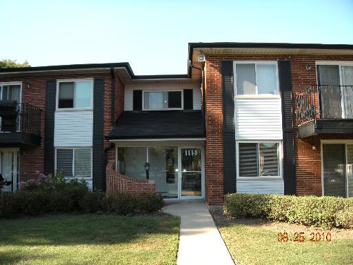 Front view of a two-story brick building with balconies and large windows.