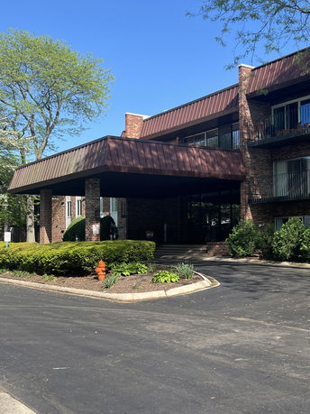 Front view of a multi-story brick building with a covered entrance and balconies.