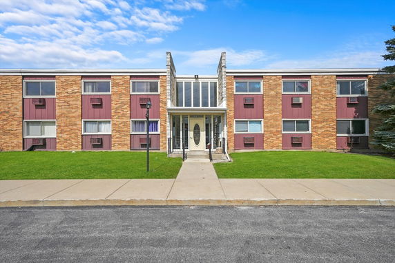 Front view of a two-story apartment building with brick exterior and multiple windows.