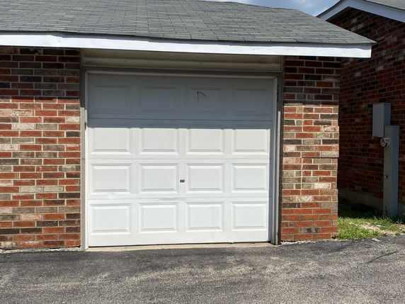 Front view of a brick garage with a white garage door.