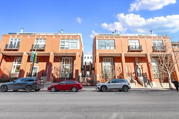 Front view of two adjacent multi-story brick residential buildings with large windows.