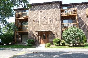 Front view of a multi-story brick apartment building with balconies.
