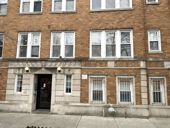 Front view of a brick multi-story building with multiple windows and a central entrance.