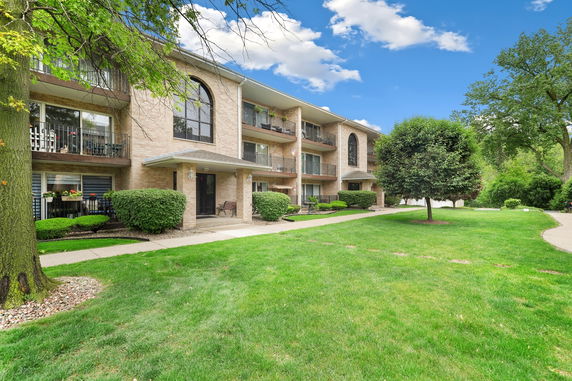 Front view of a multi-story brick apartment building with balconies.