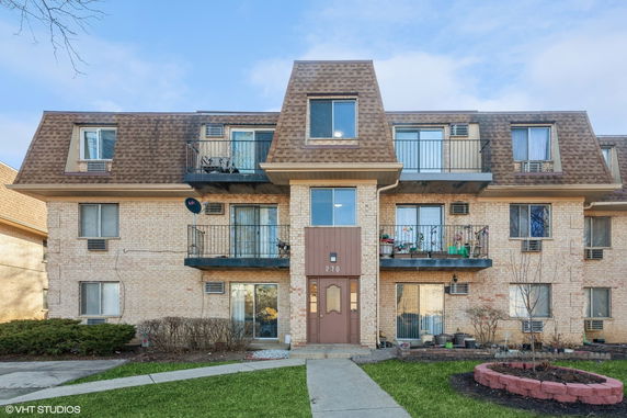 Front view of a multi-story brick residential building with balconies.