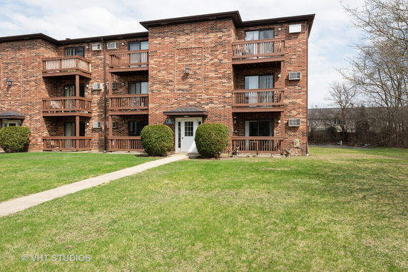 Front view of a brick apartment building with balconies.