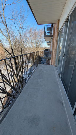 Balcony view from an apartment showing nearby trees and other balconies.
