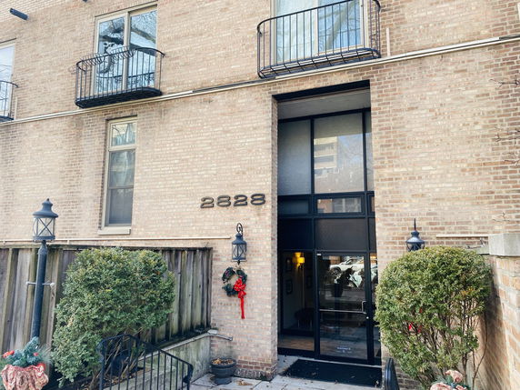 Front view of a brick building with balconies and a glass entrance.
